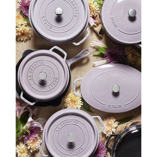 Staub | Round Cocottes - 7 qt Lilac arranged with lids and flowers, showcasing the enameled cast-iron pots' elegant design and craftsmanship.