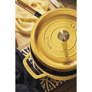 Staub | Round Cocottes - 7 qt Citron, showcasing a mustard-yellow enameled Dutch oven with a self-basting lid and lifting tool, ideal for versatile cooking.