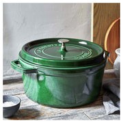Staub | Round Cocottes - 7 qt Basil, enameled cast-iron pot with lid, sits on rustic wood, paired with a black dish and cloth, ideal for braising.