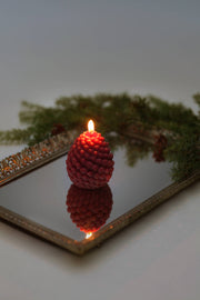 Mo&Co Home Exclusive: Sculpted Beeswax Pine Cone Candle, small size, flickers atop a gold-framed mirror tray, reflecting its elegant, festive design.