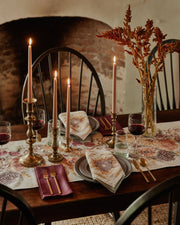 Sunflower and Wheat Dinner Napkin elegantly adorns an autumn table setting with sunflower motifs, complementing blush candles and dried flowers in a cozy fireplace ambiance.