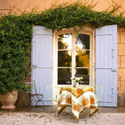 Caravan Home - Pumpkin Orange & Mustard Tablecloths: 71 x 71 drapes over a bistro table, creating a cozy, autumn-themed outdoor setting with wine and flowers.