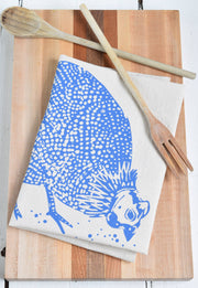 Hearth and Harrow - Organic Cotton Guinea Hen Tea Towel in Blue-violet, featuring a blue design with a wooden fork on a wooden surface.