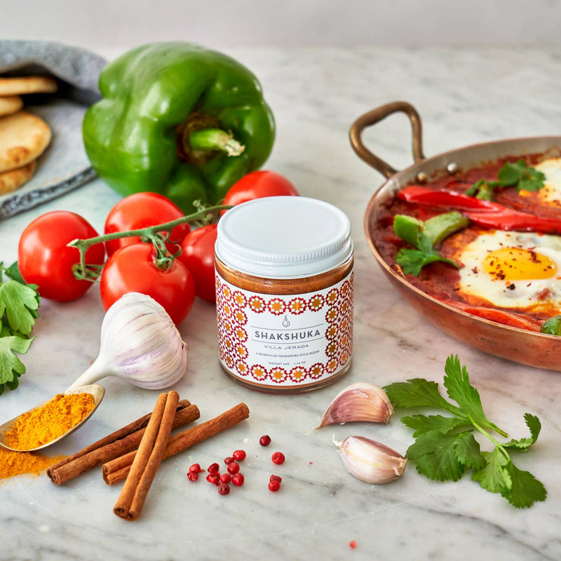 Villa Jerada - Shakshuka Blend - 50g jar alongside fresh ingredients for shakshuka on a marble surface.
