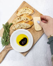 Zia Pia - Foglie Extra Virgin Olive Oil Ceramic by Galantino on a cutting board with bread, rosemary, and cheese, perfect for dipping at Athens Cooks.