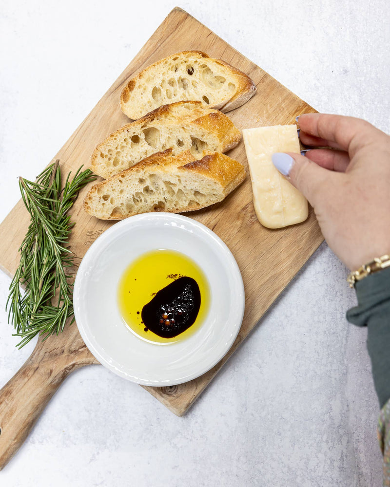 Zia Pia - Foglie Extra Virgin Olive Oil Ceramic by Galantino on a cutting board with bread, rosemary, and cheese, perfect for dipping at Athens Cooks.