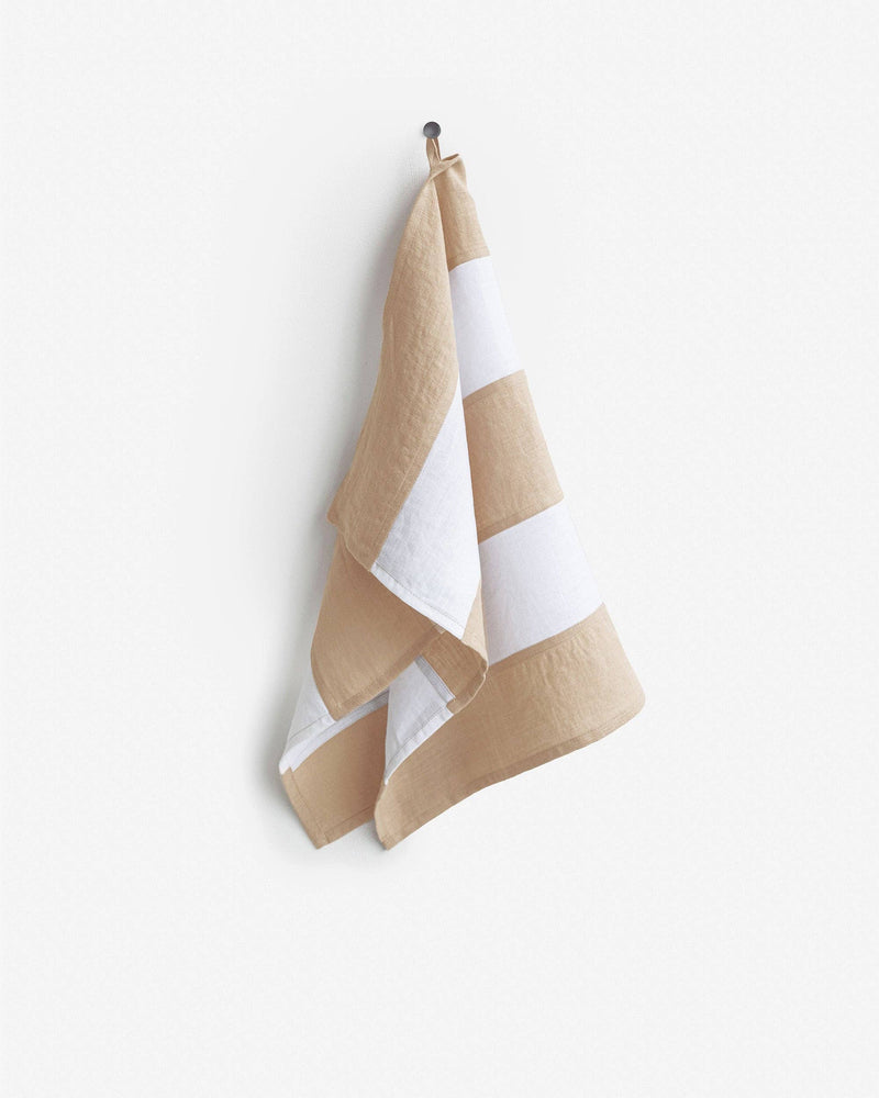 Striped linen tea towel on a hook, showcasing its hanging loop feature; part of MagicLinen's zero-waste collection, ideal for kitchens.
