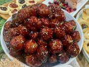 Bowl of meatballs glazed with Southern Roots Sisters - Raspberry Chipotle Jam, part of a holiday buffet, showcasing its sweet and smokey versatility.