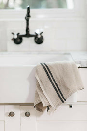 Caravan Home | Vintage Linen Natural & Black Towels draped over a white farmhouse sink, showcasing their handcrafted elegance and rustic charm, ideal for kitchen settings.