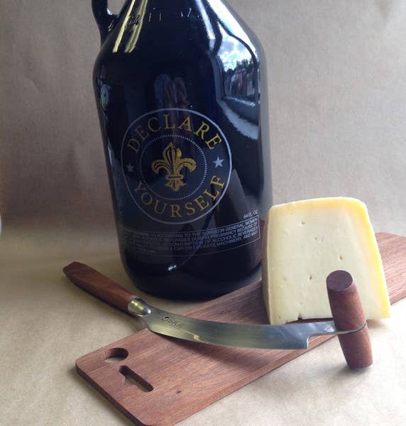 Tulip Tree Creamery - Hops: 5 Oz. Wedge cheese on wooden surface with a knife, showcasing its semi-soft texture and beer infusion. Perfect for pairing with wine or beer.