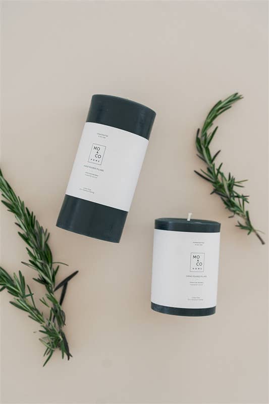 Mo&Co Home - Forest Green | 100% Beeswax Pillar Candle | All Natural, Handmade: 3x6 Inch, alongside fresh rosemary, highlighting its eco-friendly and botanical essence.