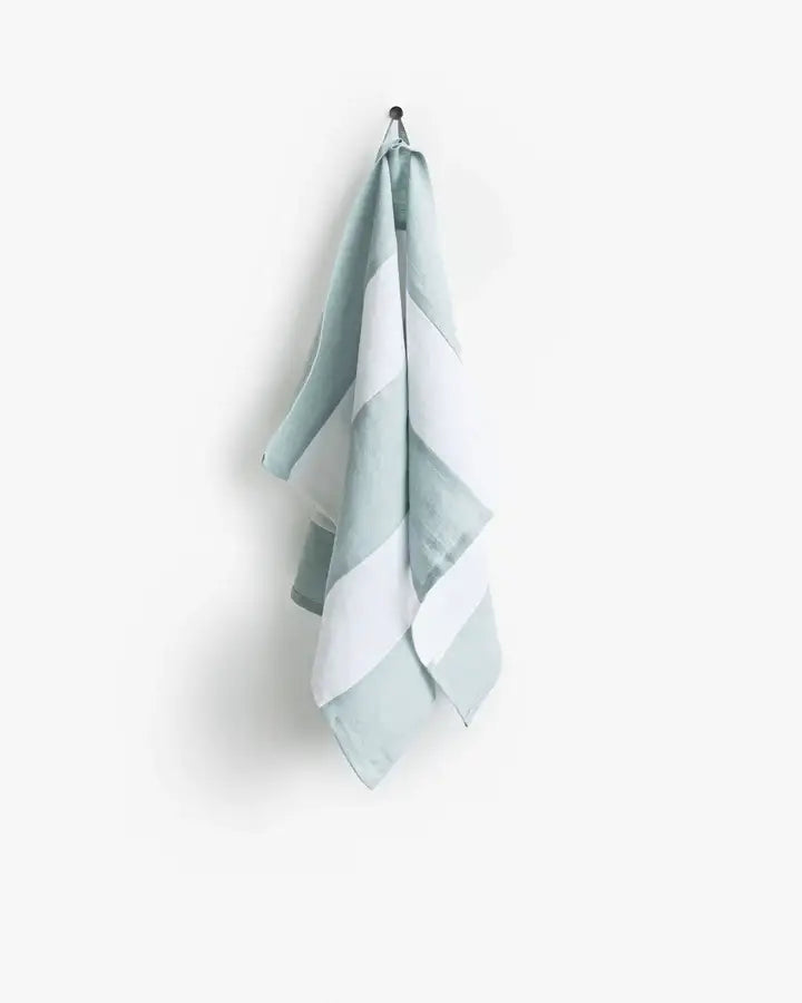 Striped linen tea towel with loop hanging on a hook, part of Athens Cooks' zero-waste collection, designed for stylish and practical kitchen use.