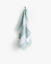 Striped linen tea towel hanging on a hook, showcasing its durable and soft texture, designed for versatility in kitchen use. Part of the zero-waste program.