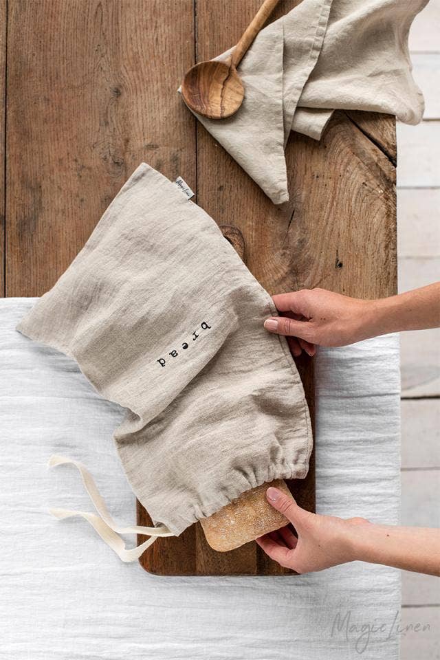 MagicLinen - Printed linen bread bag held by a person, showcasing its breathable fabric and bread logo, ideal for keeping bread fresh longer.