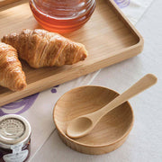 Bamboo tea spoon on a tray with croissants and honey, illustrating its eco-friendly, versatile use for stirring or serving, available at Athens Cooks.