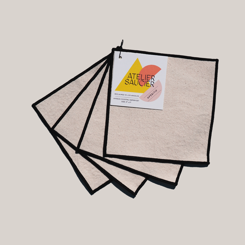 ATELIER SAUCIER - Cream Burlap Noir Cocktail Napkins | Set of 4 featuring reclaimed canvas with black edging, held by a ring and tag, measuring 5x5.
