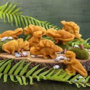 Nordic Ware | Dinosaur Cakelet Pan showing dinosaur-shaped baked goods on a wooden slab, ideal for themed parties and easy baking with nonstick cast aluminum.