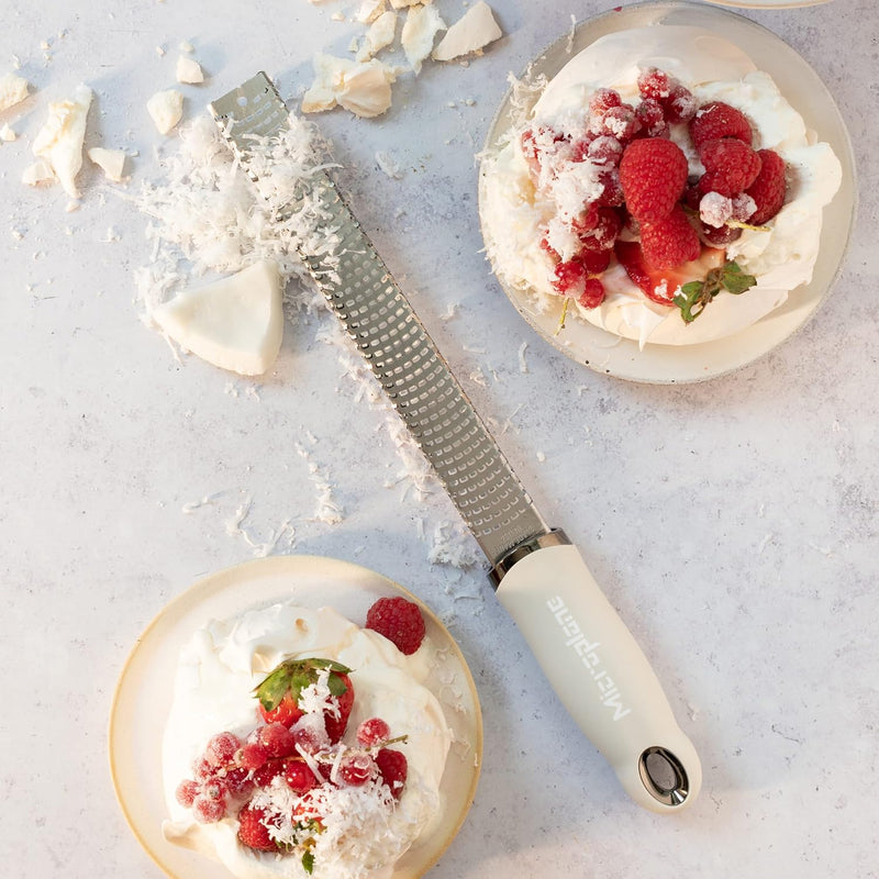 Microplane | Premium Zester, Grater - Cashmere Beige beside pavlova desserts, showcasing its fine-tooth rasp design ideal for grating toppings like white chocolate or cheese.