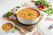 Le Creuset | Signature Round Wide Oven - White filled with chicken pozole, garnished with jalapeños and cilantro, surrounded by fresh toppings and serving essentials.