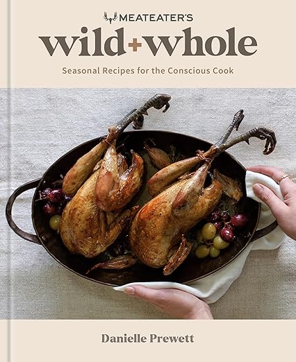 Cover of Meateater’s Wild + Whole: Seasonal Recipes for the Conscious Cook by Danielle Prewett, featuring roasted game birds with grapes in a rustic presentation.