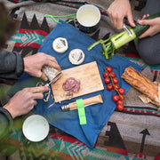 Opinel | Nomad Cooking Kit displayed during a picnic, featuring a folding knife, cutting board, and peeler, perfectly suited for outdoor culinary adventures.