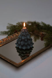 Mo&Co Home Exclusive: Sculpted Beeswax Tree Candle, small size, on ornate gold-framed mirror with pine sprigs, showcasing elegant craftsmanship and holiday nostalgia.