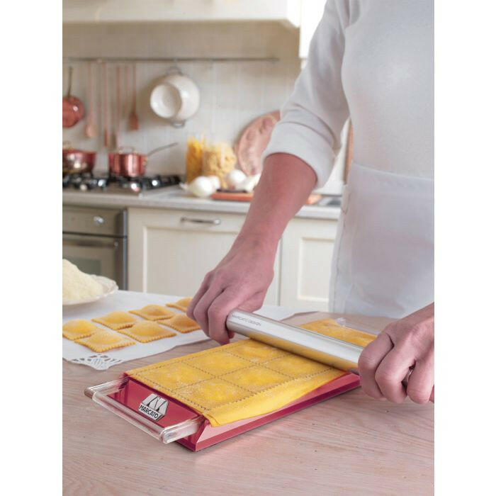 Marcato Ravioli Tablet in use, pressing pasta dough into mold on a kitchen counter, showcasing its ease for creating homemade ravioli.
