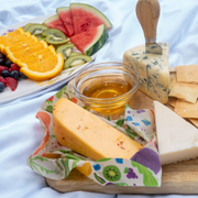 Bee's Wrap - New! Garden Party - Cut-to-Size Roll Wrap displayed with cheese and fruit, highlighting its versatile, reusable food storage capability.