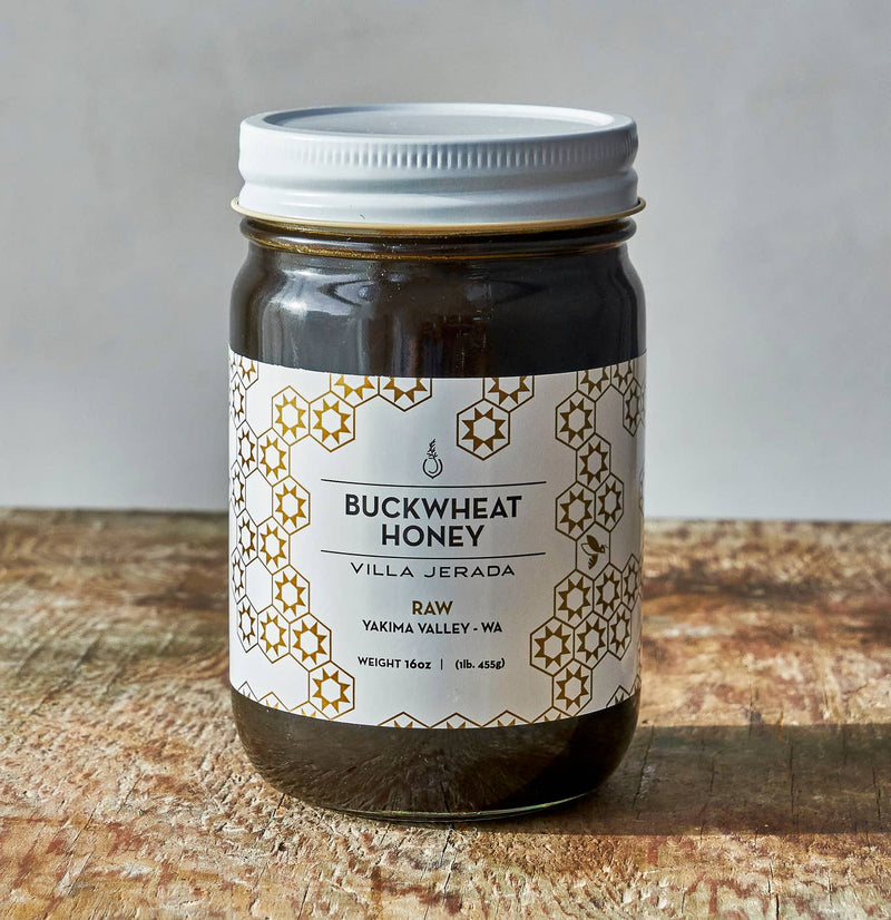 Villa Jerada - Buckwheat Honey - 1lb glass jar on rustic wood surface, featuring raw, unfiltered honey from Yakima Valley with earthy aroma and malty flavor.