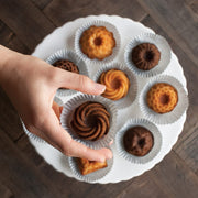 Nordic Ware | Mini Bundt Charms Pan held by a hand, showcasing six Bundt shapes for baking cakes, brownies, and more, ideal for kitchen enthusiasts.