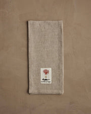 Coral & Tusk - Hedgehog with Mushrooms Tea Towel featuring a stylized red coral, gold anchor, and black whale patch, folded on a natural-toned surface.