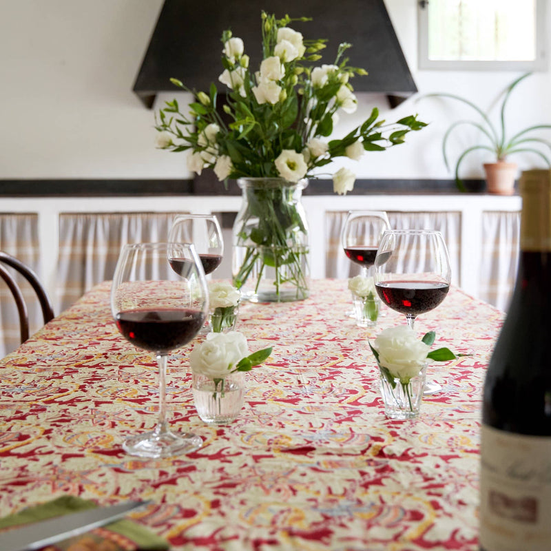 Couleur Nature - Noel Red & Green tablecloth adorns a festive dining setup with wine, votives, and blooms, perfect for holiday gatherings.