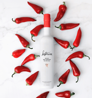 Kosterina - Spicy Red Pepper Olive Oil (375ml) bottle surrounded by red peppers, highlighting its subtle, spicy flavor perfect for enhancing various dishes.