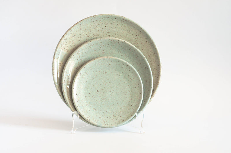 RachaelPots - Dinner Plate: Nude/White, a set of three speckled ceramic plates in various sizes on stands, showcasing handcrafted, hand-thrown pottery from Brooklyn.