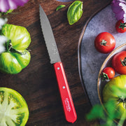Opinel | Essential Small Serrated Knife, Red with ripe tomatoes and basil on a wooden cutting board, showcasing its versatile kitchen utility.