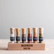 Jacobsen Salt Co. - Infused Sea Salt Gift Set with six vials, including a wooden stand, showcasing specialty salts like rosemary and habanero, perfect for culinary exploration.