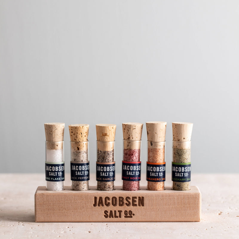 Jacobsen Salt Co. - Infused Sea Salt Gift Set with six vials, including a wooden stand, showcasing specialty salts like rosemary and habanero, perfect for culinary exploration.