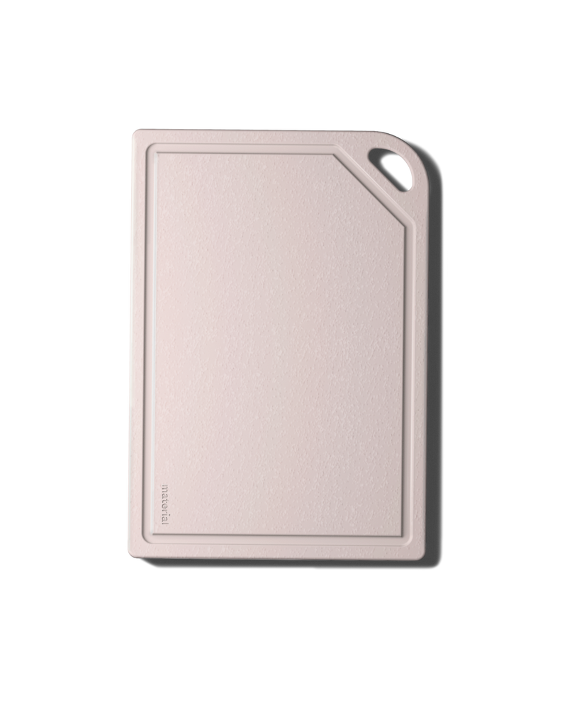 Pale-pink MK Free Board™️ with rounded corners, juice groove, and handle. Plant-based, non-porous, perfect for raw proteins; ideal for diverse culinary tasks.