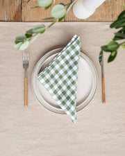 MagicLinen - Forest green gingham linen napkin set of 2 elegantly displayed on a plate, highlighting their soft texture and perfect size for dining occasions.