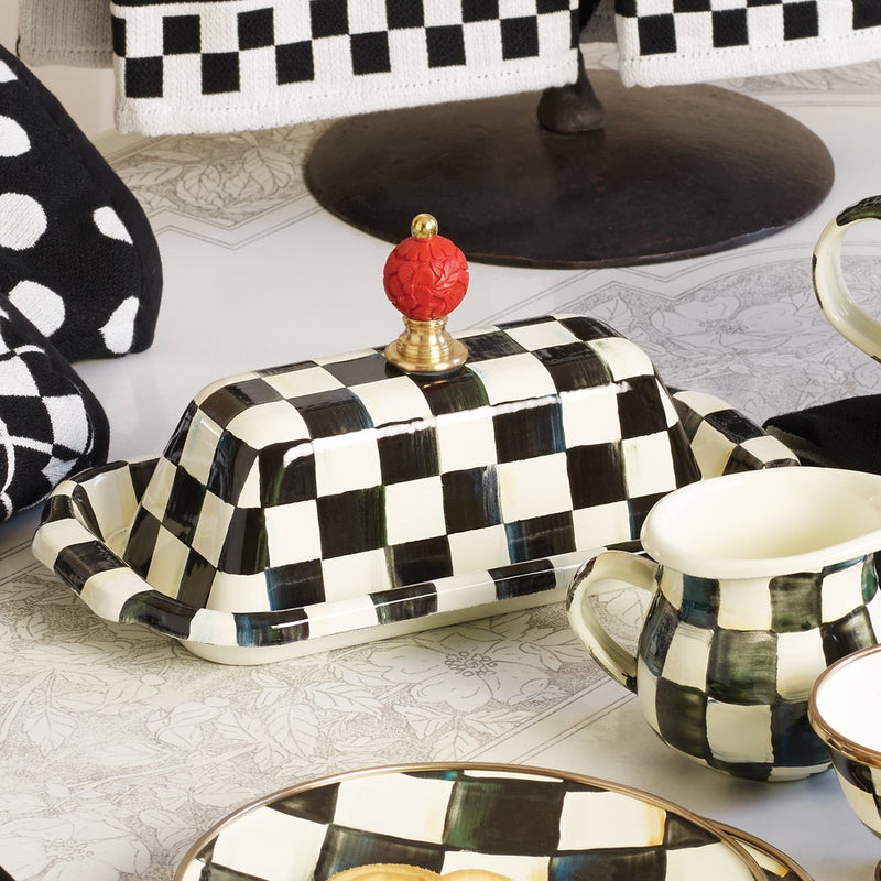 MacKenzie-Childs | Courtly Check Butter Box: A black-and-white checkerboard ceramic butter dish with a red knob, accompanied by a matching pitcher and plate.