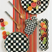 MacKenzie-Childs Courtly Check Butter Box amidst checkerboard ceramic pieces and citrus fruits, showcasing a distinctive hand-painted design with brass accents on a vibrant table.