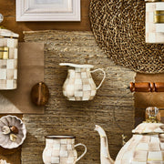 MacKenzie Childs | Mocha Check Creamer on rustic tabletop with ceramic pieces, dried botanicals, and decorative accents, showcasing handmade, mocha-check glazed design.