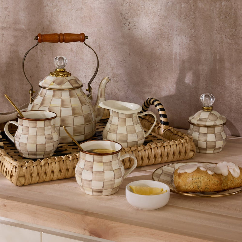 MacKenzie Childs | Mocha Check Creamer on a woven tray with matching checkered teapot, mugs, creamer jug, sugar pot, lemon slices, and pastry, showcasing Athens Cooks' curated kitchen elegance.