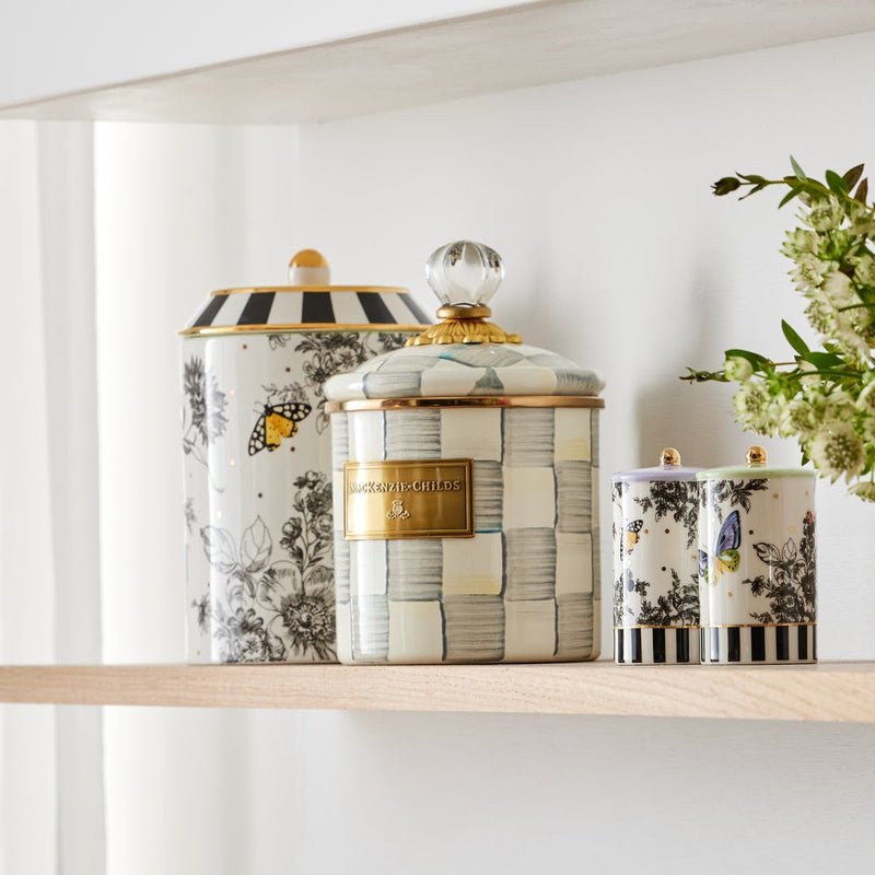 MacKenzie Childs | Sterling Check Small Canister on a wooden shelf with decorative ceramic jars, showcasing hand-painted blue-gray checks and a crystal finial for kitchen storage.