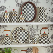 MacKenzie Childs | Courtly Check Medium Canister featuring hand-painted checkered pattern with a carved faux-cinnabar knob, displayed on white shelves with matching dishware.