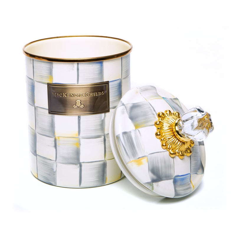 MacKenzie-Childs Sterling Check Medium Canister with hand-painted checks, brass-tone nameplate, gold-tone floral lid collar, and clear glass knob beside it.