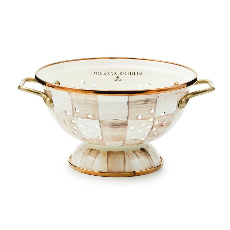 MacKenzie-Childs | Mocha Check Small Colander: Oval, enameled colander with hand-painted checkerboard pattern, warm metallic rim, raised base, and antiqued brass-finished handles, ideal for kitchen tasks.