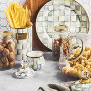 MacKenzie Childs | Cookie Jar with Sterling Check Lid on a styled kitchen counter, surrounded by decorative canisters, glass jars with nuts, and spilling pasta.