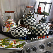 MacKenzie Childs | Courtly Check with Bird Tea Kettle, 3 QT, on a stainless-steel range, surrounded by cookware and a baking pan with vegetables.