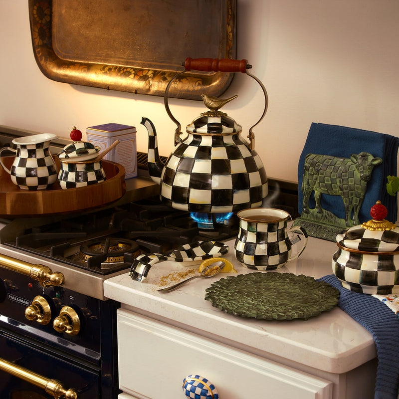 MacKenzie Childs Courtly Check with Bird Tea Kettle, 3 QT on a stove, part of a coordinated checkerboard tea set, embodying whimsical kitchenware charm.